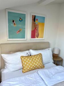 a bed with white pillows and two pictures on the wall at Villa Agapella 250m from the beach - Agapella Apartamemty in Sopot +134 photos