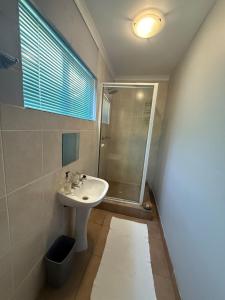 a bathroom with a sink and a shower at Barking Beach Cottage, Sandbaai - Pet Friendly in Hermanus