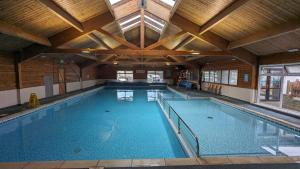 a large indoor swimming pool with a wooden ceiling at Beehive 136 snowdon summit 100 in Barmouth