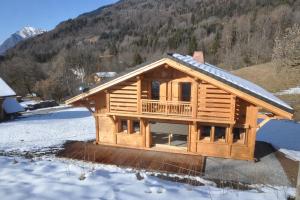 a log cabin with snow on the ground at Chalet Le Villard Samoens in Samoëns