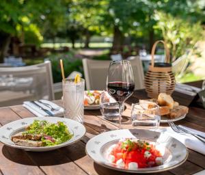 a wooden table with plates of food and a glass of wine at Hotel Demeures de Campagne Château de Fontainebleau in Fontainebleau