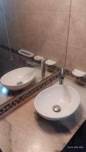 a bathroom with two white sinks on a counter at Posada del Arroyo in Las Rabonas