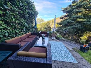eine Terrasse mit einem Sofa und einem Glastisch in der Unterkunft Ferienwohnungen Dorfliebe Dörnberg GARTENBLICK in Bestwig