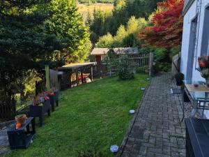 ein Hinterhof mit Rasen, Bänken und Zaun in der Unterkunft Ferienwohnungen Dorfliebe Dörnberg GARTENBLICK in Bestwig