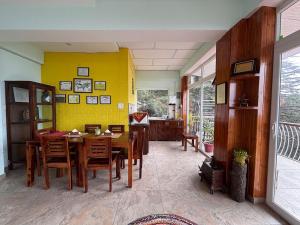 a dining room with a table and a yellow wall at Fiddlehead Fern in Dharmsala