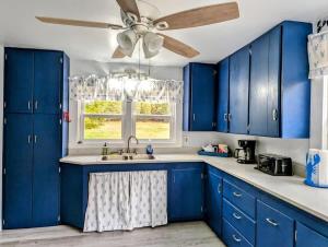 una cucina con armadi blu e un ventilatore a soffitto di Beach Vibes Acadia Cottage Fire pit Family Acadia sleeps 8 a Sullivan