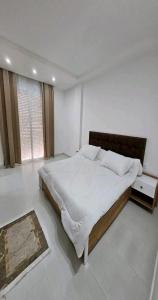 a white bedroom with a large bed and a window at 909 apartment in Amman