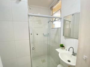 a white bathroom with a shower and a sink at Conforto perto do Mar em São Vicente! in São Vicente +10 photos