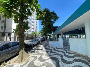 a street with cars parked next to a building at Conforto perto do Mar em São Vicente! in São Vicente