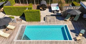 OosterzeleLa maison de Nikolas的带遮阳伞和椅子的游泳池的俯视图