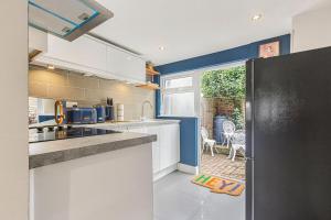 eine Küche mit einem schwarzen Kühlschrank und einer Terrasse in der Unterkunft OnSiteStays - Cute Cottage In Barcombe in Lewes
