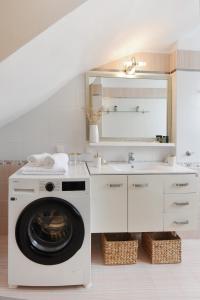 uma casa de banho branca com uma máquina de lavar roupa e um lavatório em Aurum Syros em Hermópolis