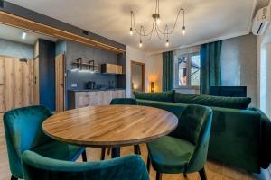 a living room with a table and green chairs at Villa Park Zwierzyniec in Zwierzyniec