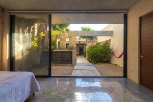 メリダにあるCasa Pepen by Kanaa - Colonial Luxury with a Private Outdoor Pool and Garden in Central Meridaのガラスドアから中庭の景色を望むベッドルーム1室