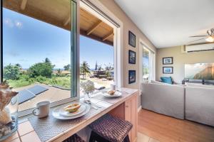 a living room with a table and a large window at Hale Kahana'lu in Koloa