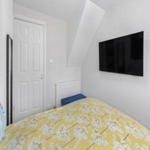 ein Schlafzimmer mit einem Bett und einem Flachbildfernseher in der Unterkunft OnSiteStays - Cute Cottage In Barcombe in Lewes