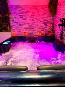 a hot tub with purple lights in a room at le cocon de gepetto spa privatif in Fussy