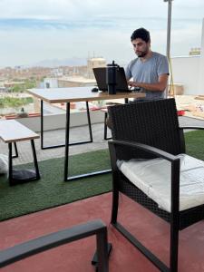 a man sitting at a table with a laptop at Galicia Lodgement in Lima