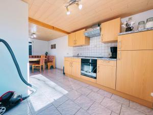 a kitchen with wooden cabinets and a table with a vacuum at Ferienwohnung 2 Wald & See in Zirchow