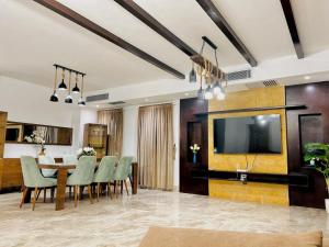 ein Esszimmer mit Tisch und Stühlen und einem Fernseher in der Unterkunft VIP-Luxury private villa standalone Emaarmasr in New cairo
