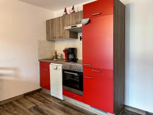 Il comprend une cuisine équipée de placards rouges et d'un réfrigérateur rouge. dans l'établissement Ours Living Tauernkogel - inkl Sauna, à Hollersbach im Pinzgau 5 autres photos