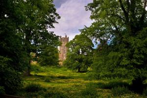 a building in the middle of a field with trees at Narrowboat Puzzle in Ely