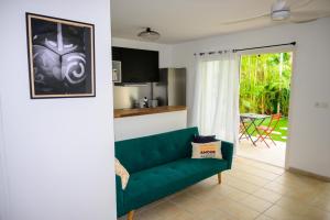 a living room with a green couch and a kitchen at La parenthèse in Courcelles Sucrerie