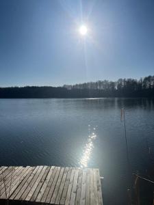 a dock on a lake with the sun on the water at Biały Domek in Lutol Mokry +3 photos