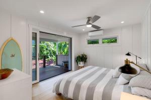a white bedroom with a bed and a balcony at Camp Magic 2 in Hanalei