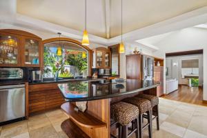 a kitchen with wooden cabinets and a bar with stools at Kapiolani - As seen on HGTV in Princeville