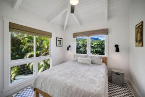 a white bedroom with a bed and two windows at Camp Magic 1 in Hanalei