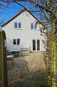 a white house with a picnic table in front of it at Farthing Cottage in Norwich