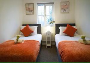 two beds with orange pillows in a room at 5 Bedrooms, Sleeps 10, Free Parking, Near NEC & Airport, Contractors in Solihull