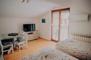 a bedroom with two beds and a desk and a television at Bisera Apartments in Ohrid