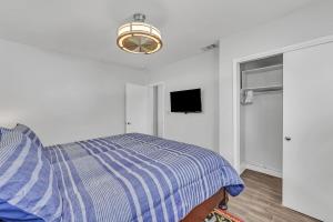 Un dormitorio con una cama y un televisor en la pared. en 3Bed Modern Home Family Friendly Heated Pool, en Fort Lauderdale