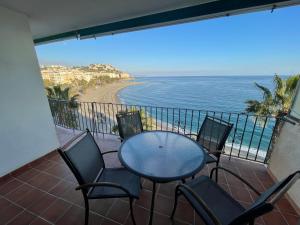 a balcony with a table and chairs and the ocean at Primera línea de playa espectacular 3 dormitorios in Almuñécar