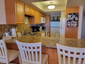a kitchen with white chairs and a counter with a sink at 409 - 2/2 Stunning Condo Ocean View in New Smyrna Beach +33 photos