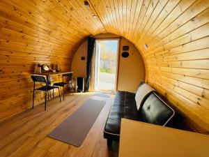 sala de estar con sofá de cuero negro en una pared de madera en Woodside Pod, en Corpach