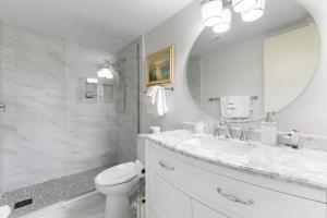 a bathroom with a sink and a toilet and a mirror at Charming 2-Bedroom, 2-Bath Condo with Golf Course Views in Isla Del Sol in Point Brittany +19 photos