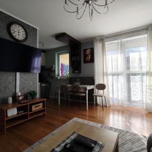 een woonkamer met een tafel en een klok aan de muur bij Współczesny Apartament Gdańsk in Borkowo
