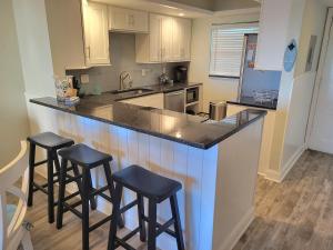 a kitchen with three bar stools at a counter at 202 - Adorable 1 bedroom unit - sleeps 6 in Edgewater
