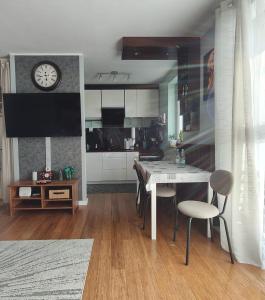 een keuken met een tafel en stoelen en een klok bij Współczesny Apartament Gdańsk in Borkowo