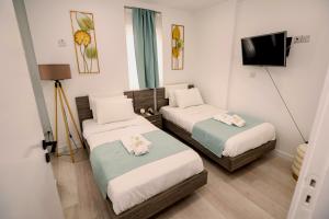 een kleine kamer met 2 bedden en een televisie bij Lazuli Sea View Beachfront Ap 21 in Larnaka