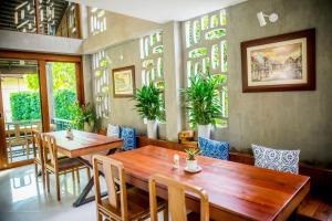 a dining room with two tables and chairs and plants at Chu Hotel in Chiang Mai