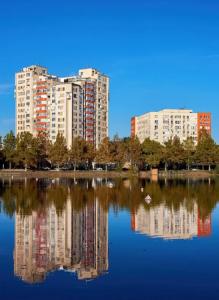 a reflection of buildings in a lake with buildings at Ботаника , парк долина роз аеропорт in Chişinău