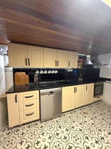 Una cocina con gabinetes blancos y encimeras negras. en 3-Story Bohemian Greek House w Garden, en Ayvalık