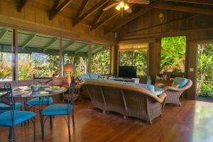 a living room with a table and chairs and windows at Wainiha Beach Hale in Wainiha