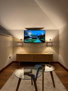 a living room with a tv and a glass table at Hotel Boutique Villa de Noreña in Noreña