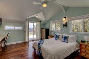 a bedroom with a bed and a desk and windows at Paradise Ocean View in Keaau