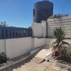 a house with a fence and a palm tree at Seaside Retreat Guest Suite - Encil ger y môr in Aberystwyth